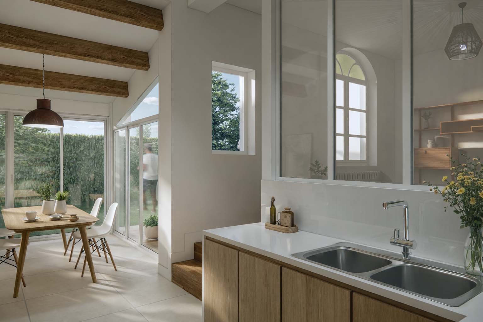 Cuisine ouverte rénovée à Angoulême avec verrière intérieure, plan de travail clair, mobilier en bois, poutres apparentes et salle à manger baignée de lumière naturelle.