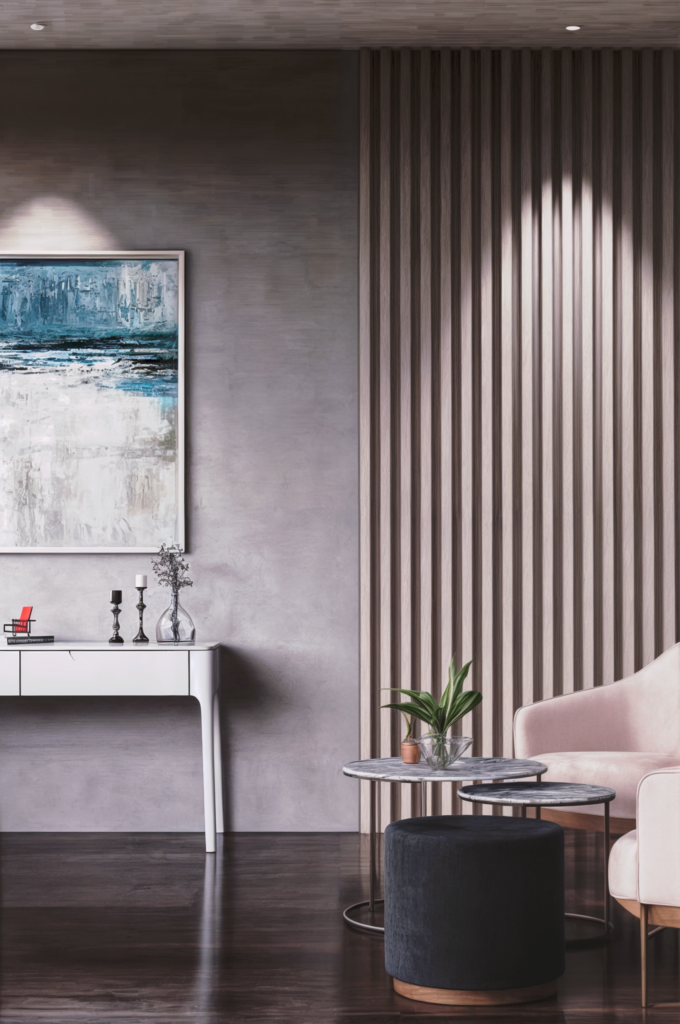 Image du salon après la rénovation par BYAA Inside à Bordeaux Pey-Berland. On y voit un mur en pierre, un canapé gris, des fauteuils roses, une table basse ronde et des touches de verdure.